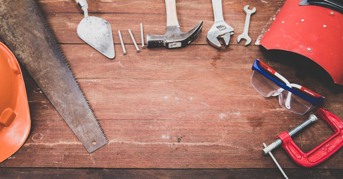 Flat lay of workshop tools on a rustic wooden table for DIY projects
