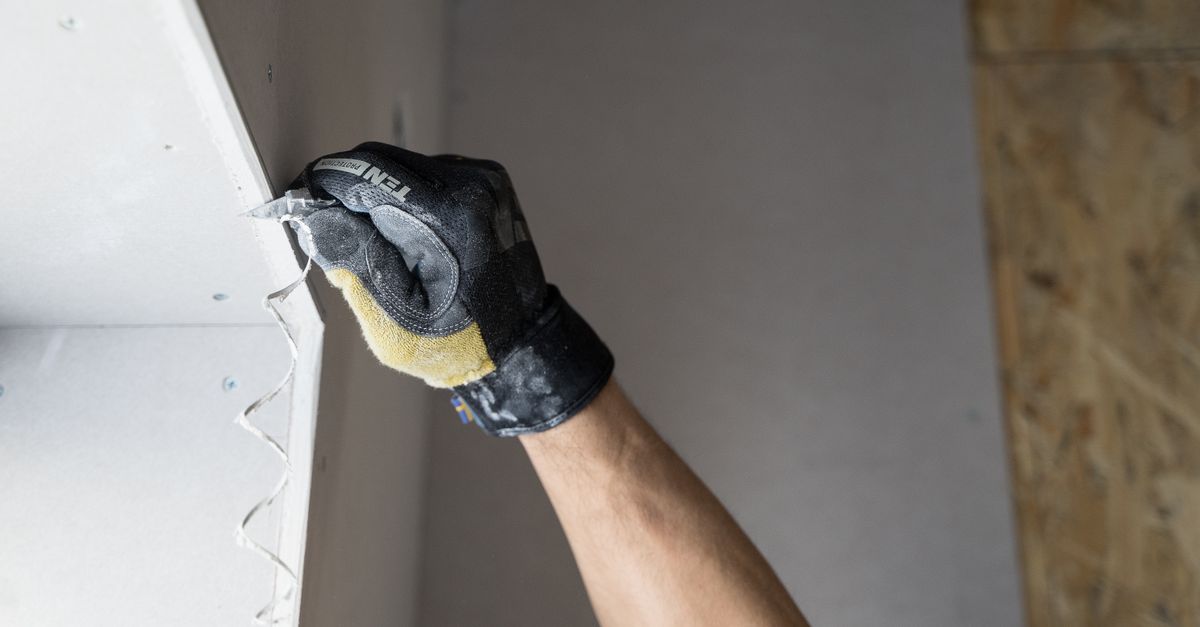 Worker applying plaster to a wall during a drywall repair project
