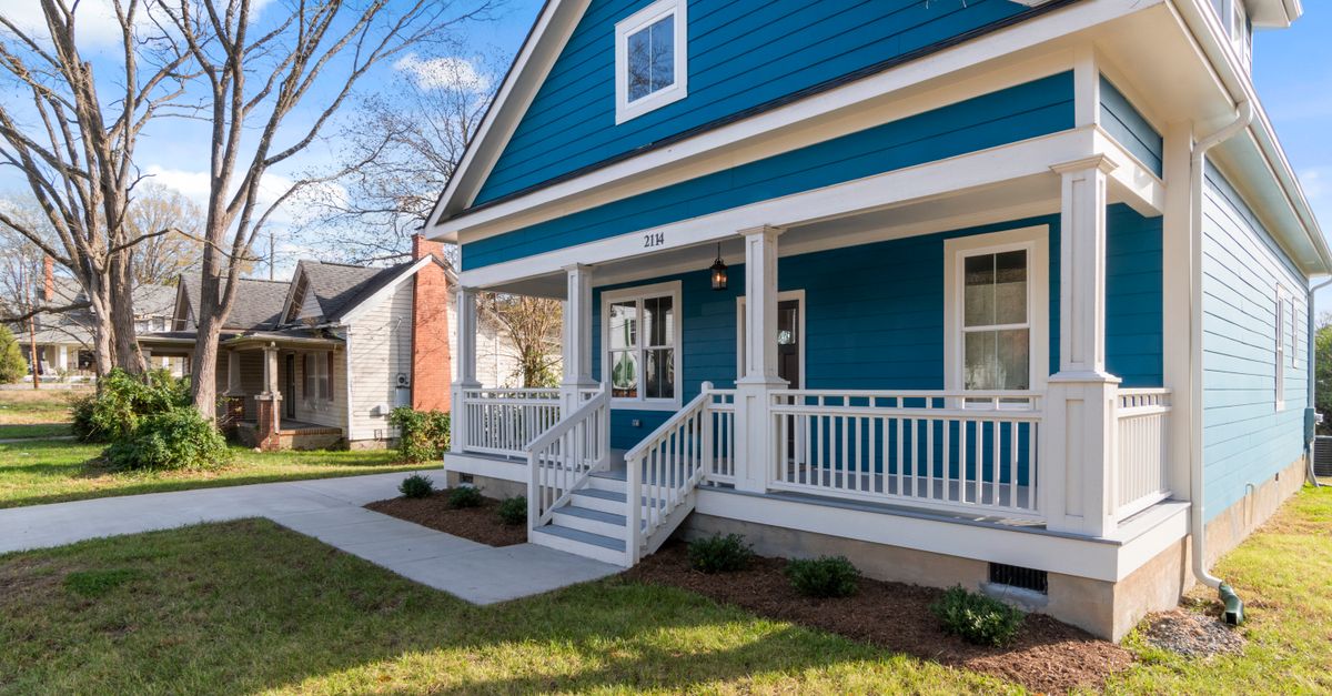 Cozy blue suburban house with white front porch and lush surroundings